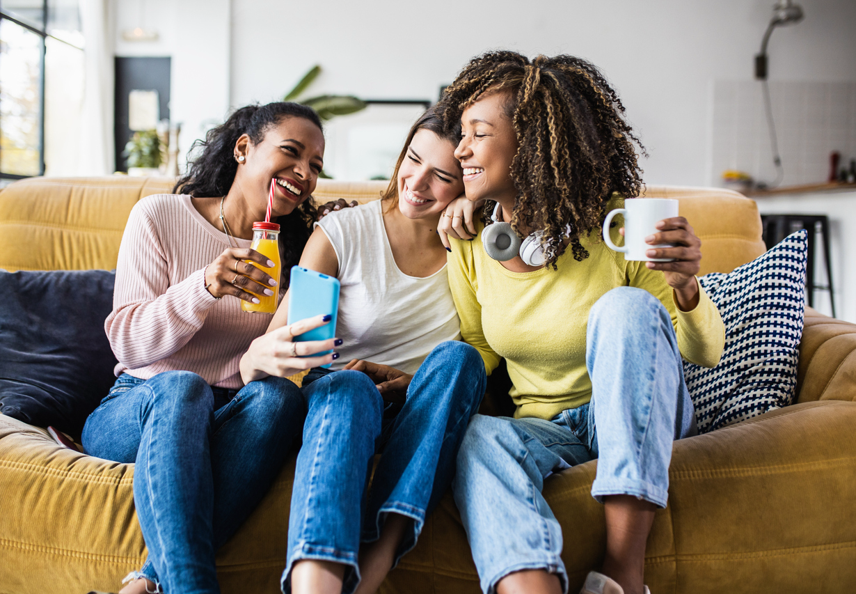 three women sitting on couch smiling and talking